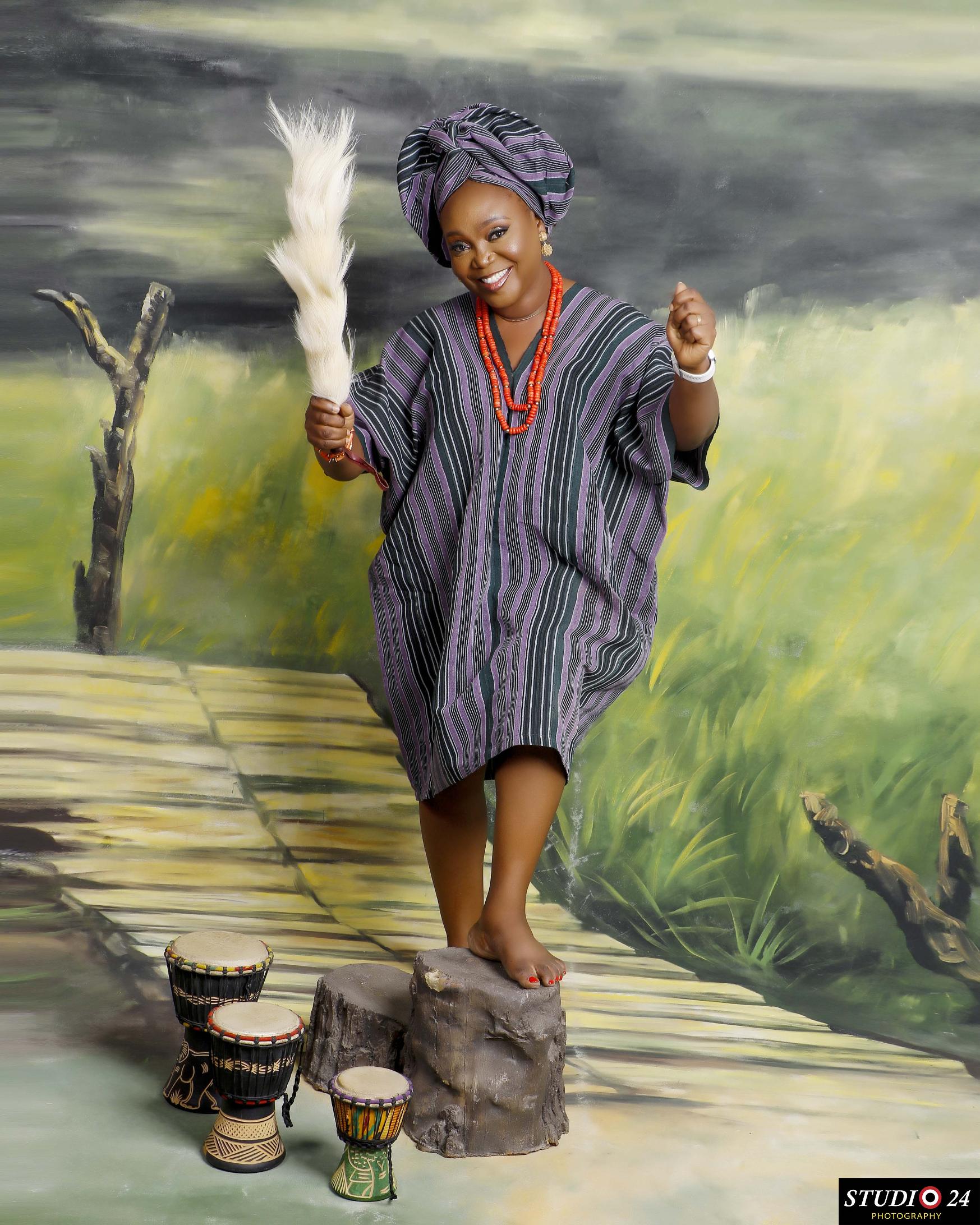 Temitope in traditional dress and headwrap, beside drums